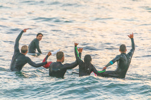 Grupo de surfistas en el mar al atardecer